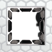 Square drain grate with glossy black openings along edges and darker central slot shapes