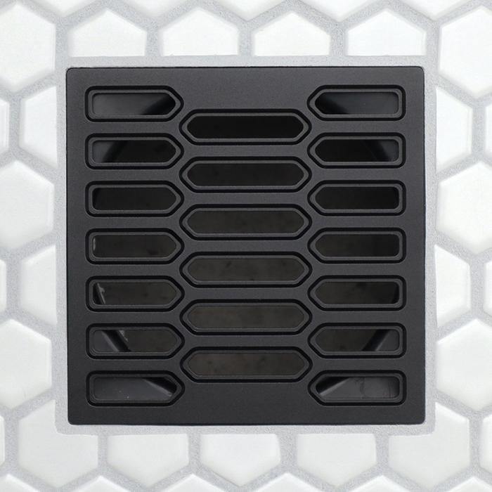 Matte black drain grate with repeating rounded rectangular slots and central elongated channel