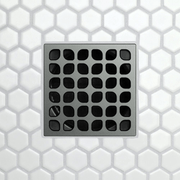 Drain grate with rounded square opening grid on dark gray metal.