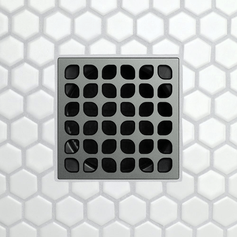 Drain grate with rounded square opening grid on dark gray metal.