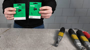 Person holding two green DISTAR packaging against a tiled wall background with tools on a counter.