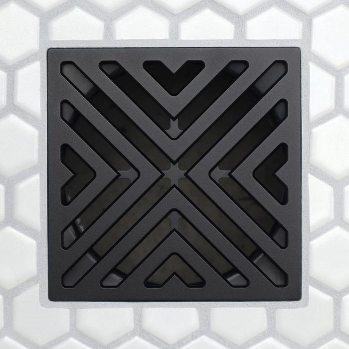 Square matte black drain grate with chevron V openings and dark surrounding channels