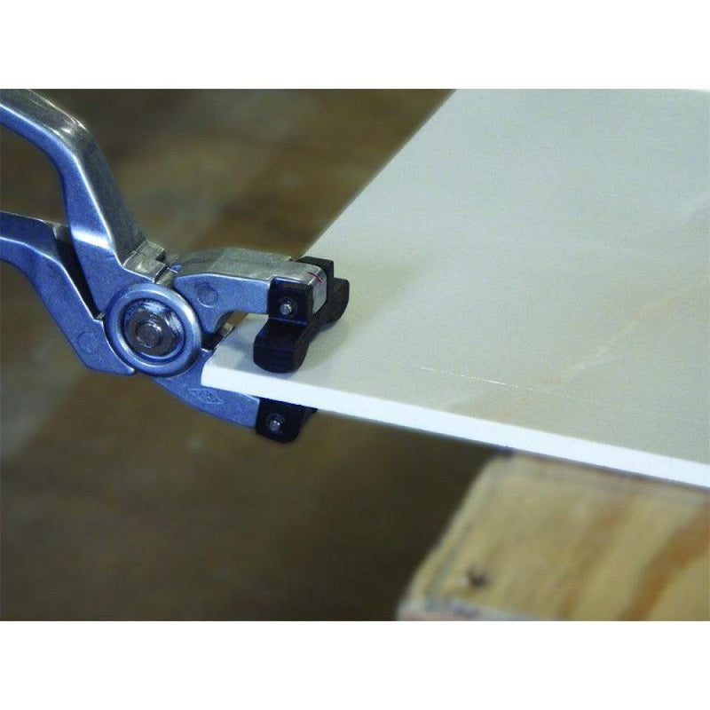 Worker using the Alpha EX Glass pliers to break a piece of thin panel porcelain. the plastic jaws keep the material from becoming marred