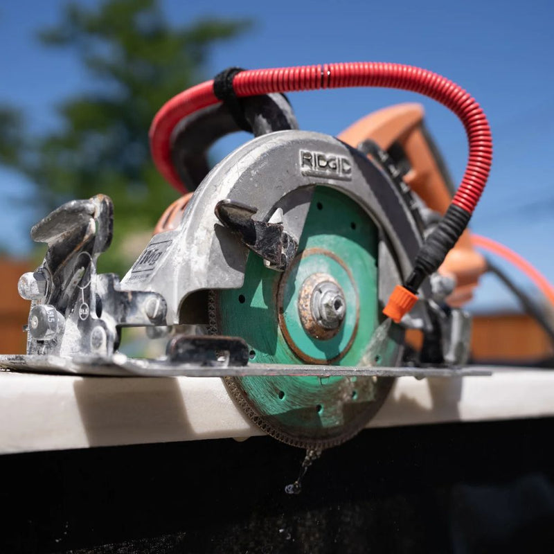Hydrotail attached to Rigid circular saw with water flowing for dust control during masonry cutting